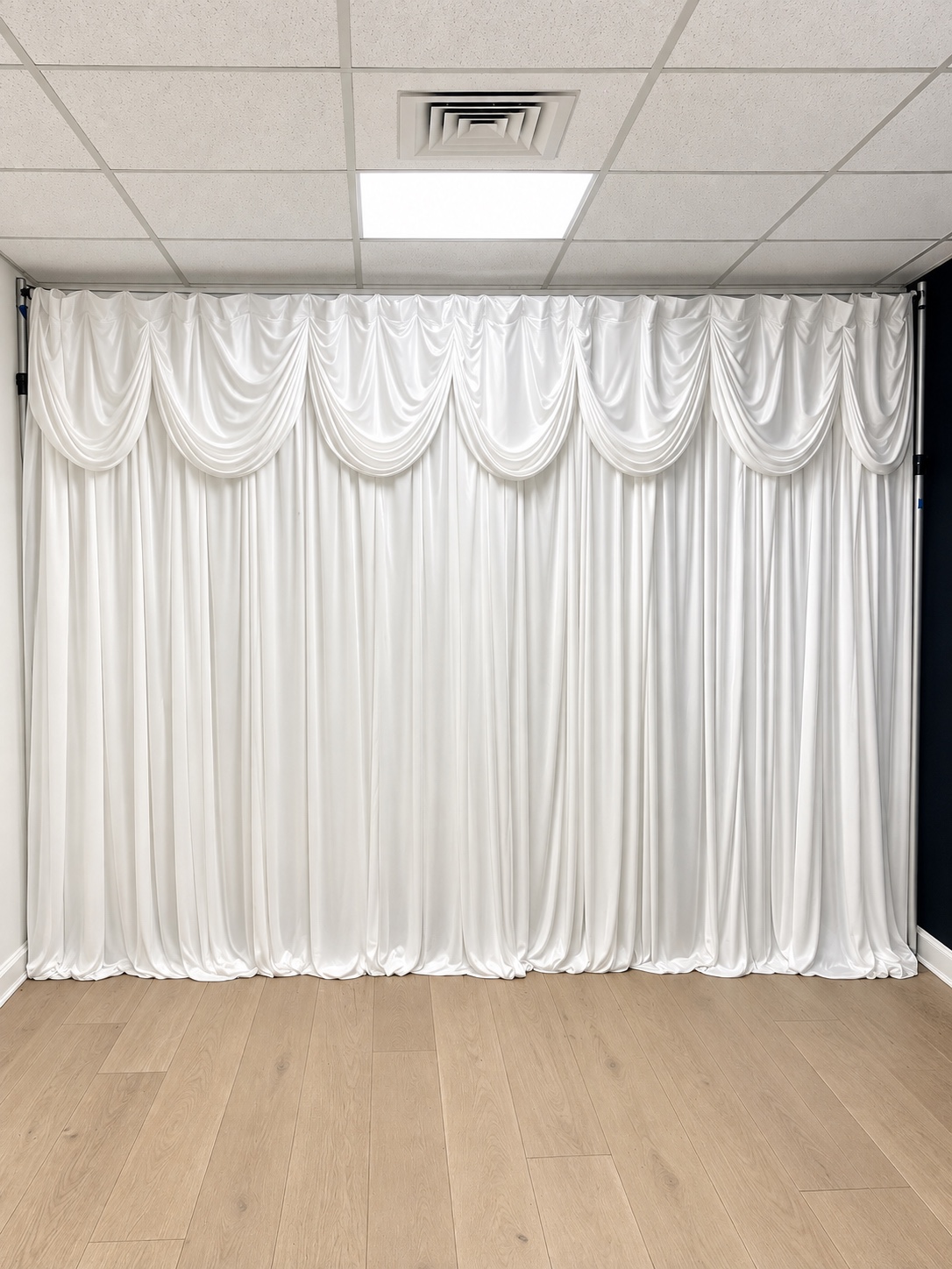 Full-width white draped event backdrop with elegant swags